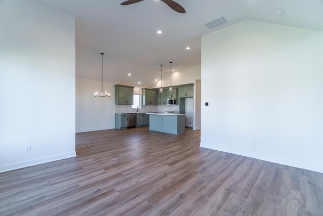 unfurnished living room with dark wood-type flooring, vaulted ceiling, and ceiling fan with notable chandelier