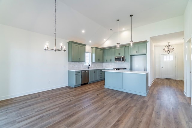 kitchen with an inviting chandelier, appliances with stainless steel finishes, decorative light fixtures, and wood-type flooring