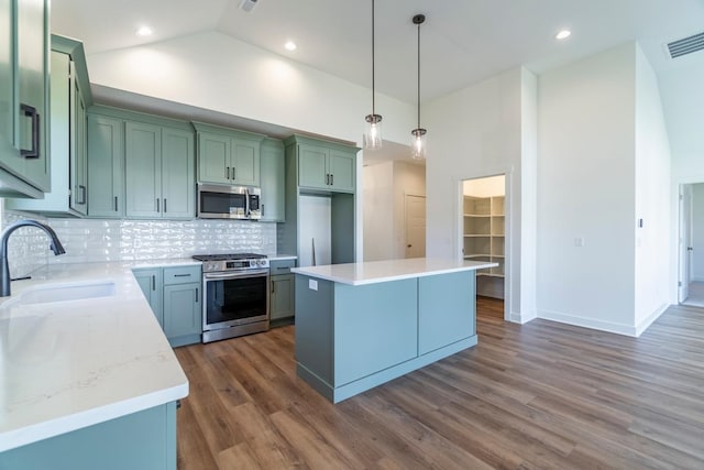 kitchen featuring sink, a center island, stainless steel appliances, dark wood-type flooring, and high vaulted ceiling