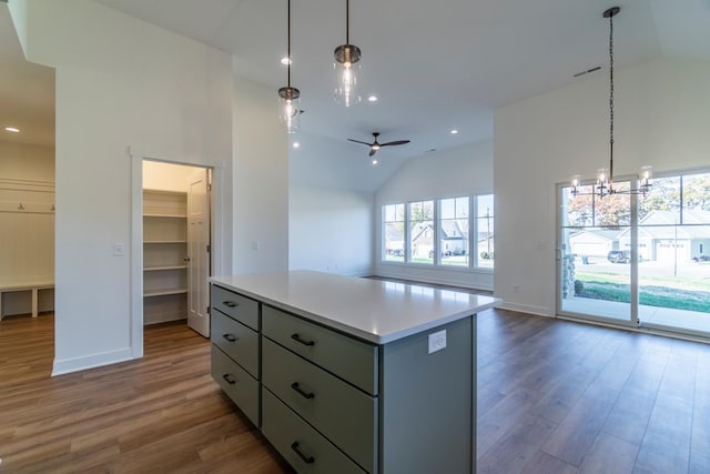 kitchen with dark hardwood / wood-style floors, decorative light fixtures, ceiling fan with notable chandelier, and a kitchen island