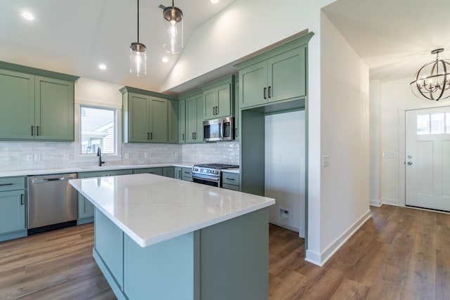 kitchen featuring appliances with stainless steel finishes, green cabinets, light wood-type flooring, and hanging light fixtures