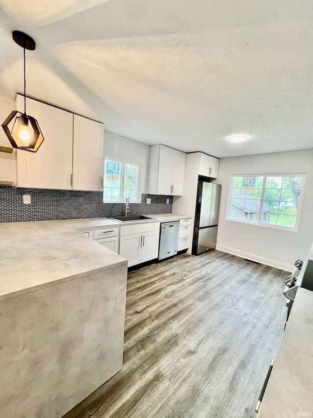 kitchen with stainless steel appliances, a healthy amount of sunlight, decorative light fixtures, and white cabinets