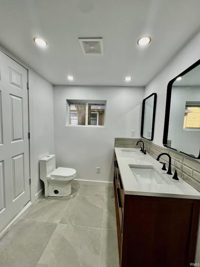 bathroom with double sink vanity, toilet, tile patterned flooring, and a healthy amount of sunlight