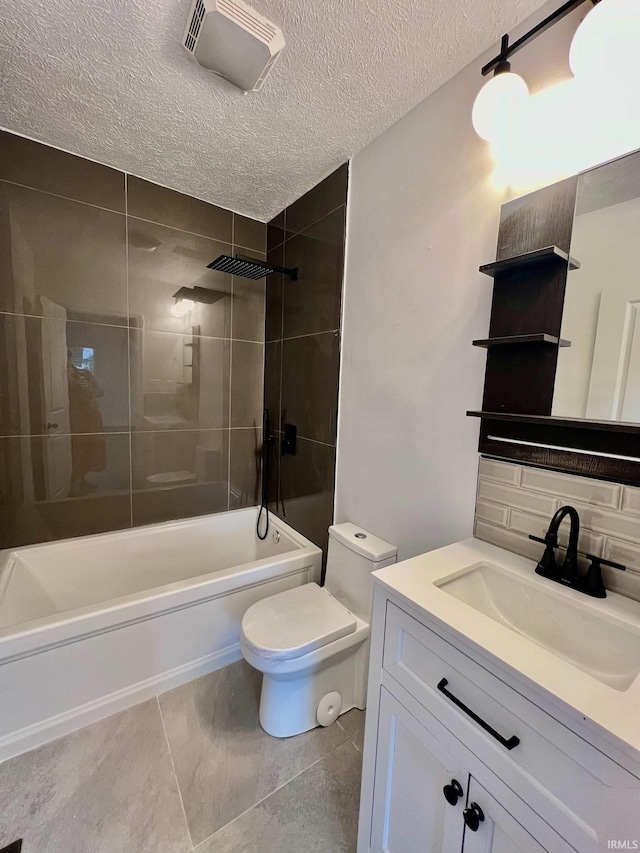 full bathroom with vanity, tile patterned flooring, a textured ceiling, toilet, and tiled shower / bath combo