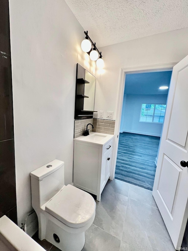 bathroom with hardwood / wood-style floors, vanity, tasteful backsplash, a textured ceiling, and toilet