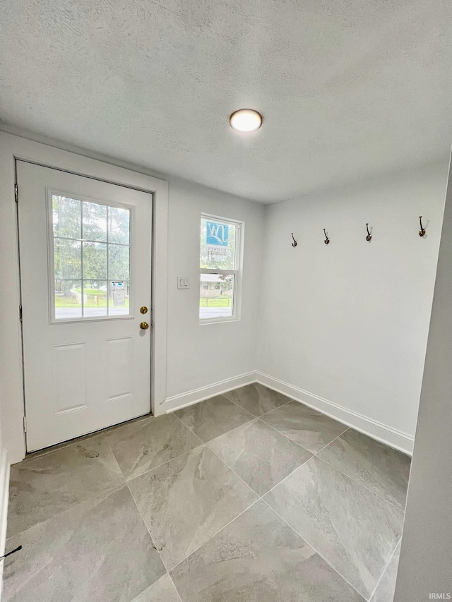 entryway with light tile patterned floors and a textured ceiling