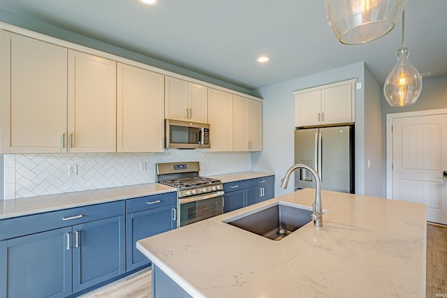 kitchen featuring sink, appliances with stainless steel finishes, hanging light fixtures, light stone counters, and a center island with sink