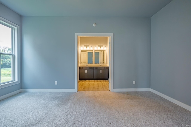 unfurnished bedroom featuring connected bathroom and light carpet