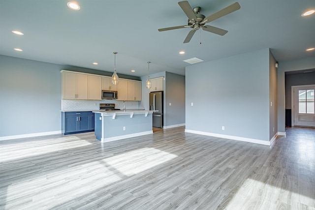 kitchen featuring a breakfast bar, appliances with stainless steel finishes, hanging light fixtures, a center island, and decorative backsplash