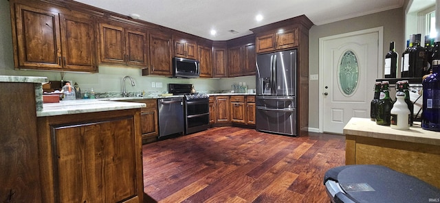 kitchen featuring dark wood finished floors, a sink, light countertops, appliances with stainless steel finishes, and crown molding