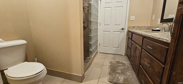 full bathroom featuring toilet, tiled shower, tile patterned flooring, baseboards, and vanity