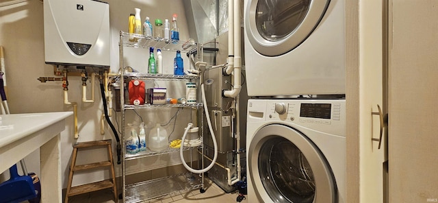 laundry area with laundry area, stacked washer / drying machine, and tankless water heater