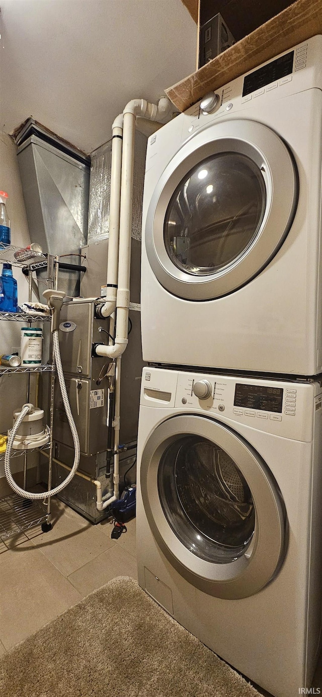 laundry room with tile patterned flooring and stacked washer and clothes dryer