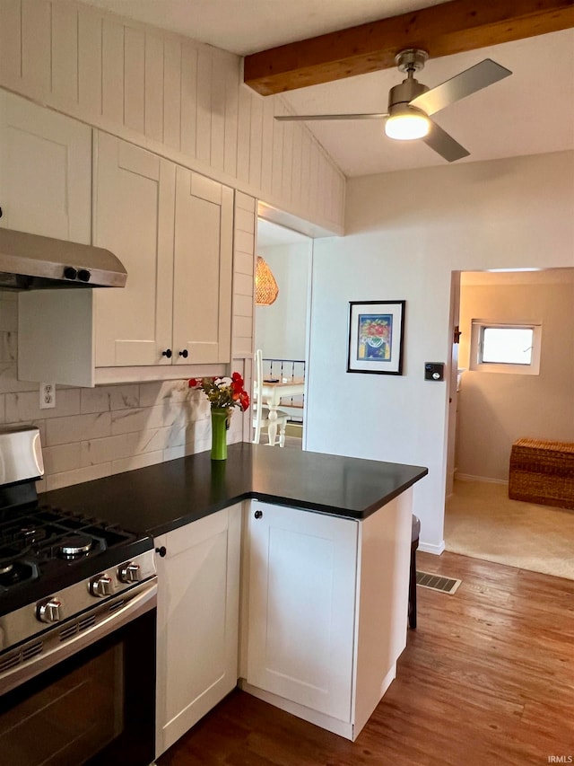 kitchen featuring hardwood / wood-style flooring, kitchen peninsula, and stainless steel gas range oven