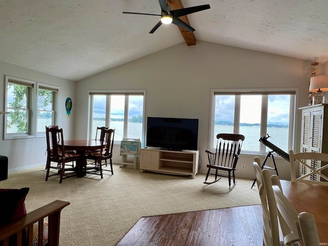 carpeted living room with lofted ceiling with beams, ceiling fan, and a textured ceiling