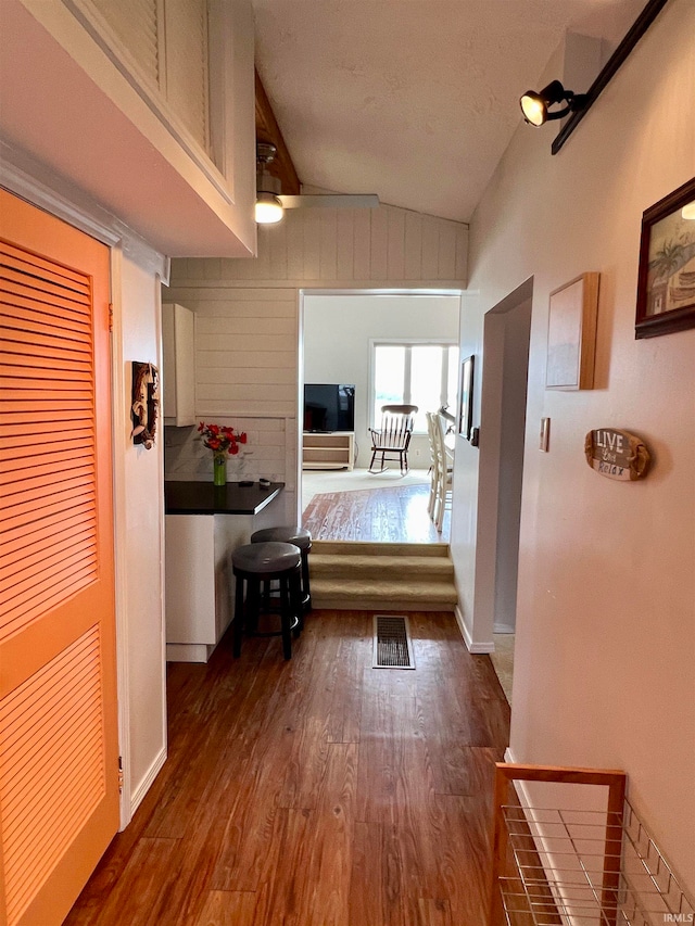 corridor featuring dark wood-type flooring and lofted ceiling