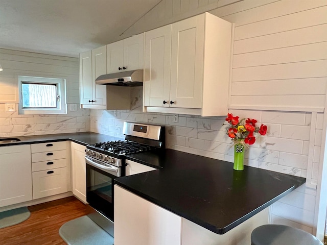 kitchen featuring gas range, white cabinetry, dark hardwood / wood-style floors, tasteful backsplash, and kitchen peninsula