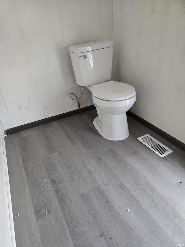 bathroom with hardwood / wood-style floors, tile walls, and toilet