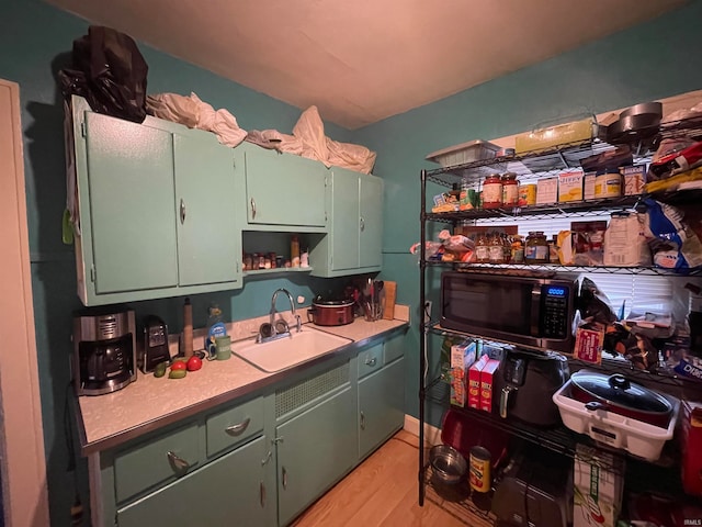 kitchen with light wood-type flooring, sink, and green cabinets