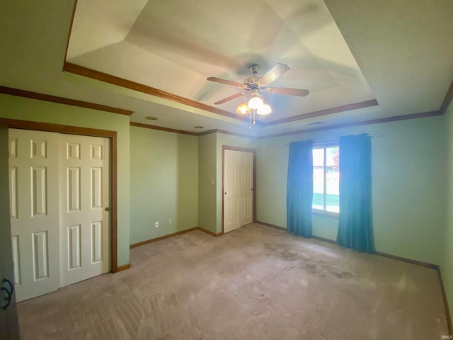 unfurnished bedroom with ceiling fan, light carpet, and a tray ceiling