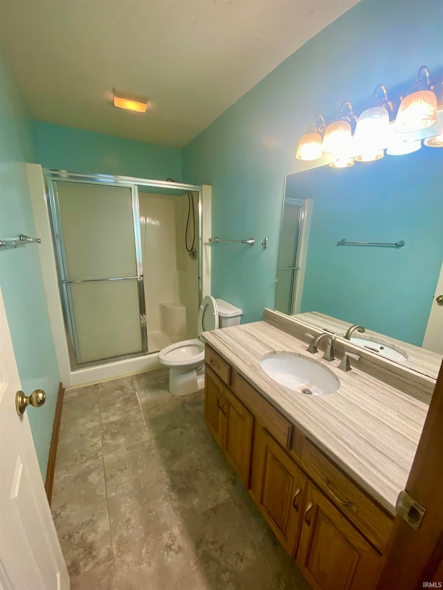 bathroom featuring tile patterned flooring, a shower with shower door, vanity, and toilet