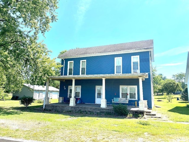 rear view of house featuring a porch and a lawn