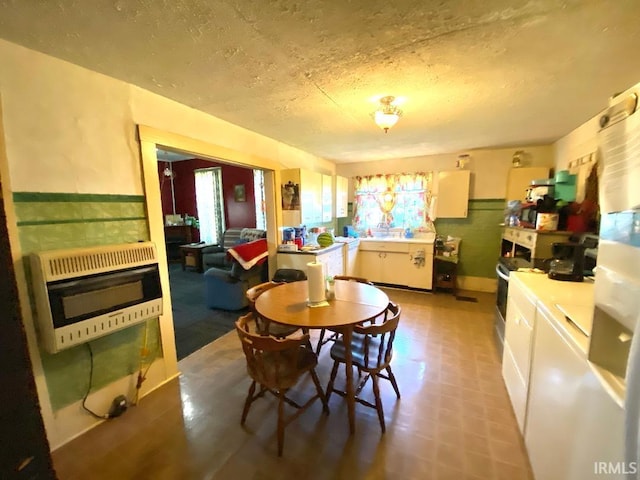 dining space with a healthy amount of sunlight, heating unit, and a textured ceiling