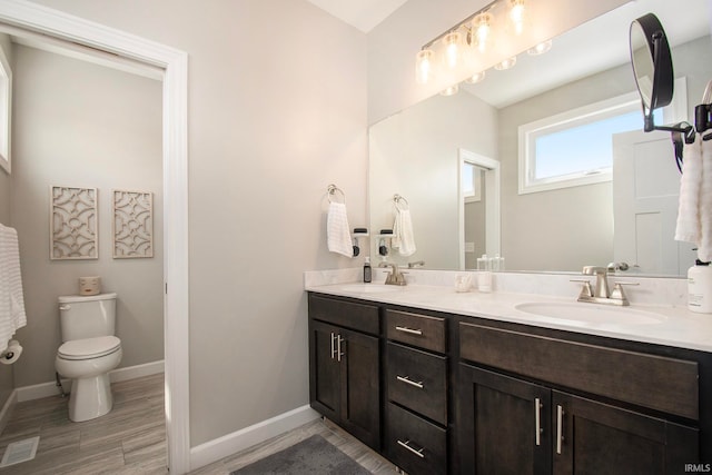 bathroom with toilet and double sink vanity