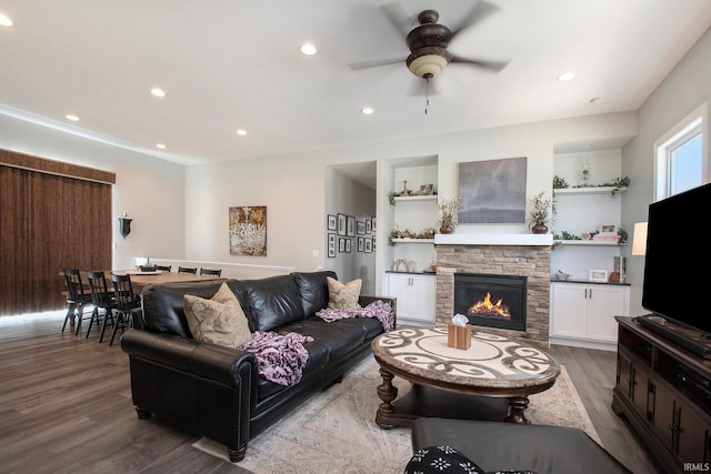 living room with ceiling fan, a stone fireplace, and hardwood / wood-style flooring