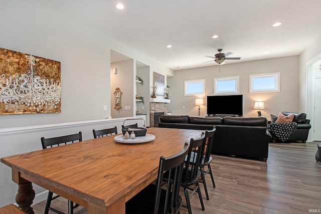 dining space with a fireplace, ceiling fan, and wood-type flooring