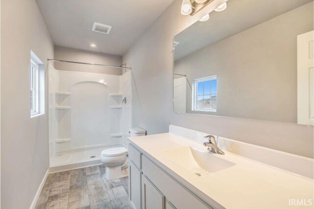 bathroom featuring vanity, toilet, wood-type flooring, and a shower