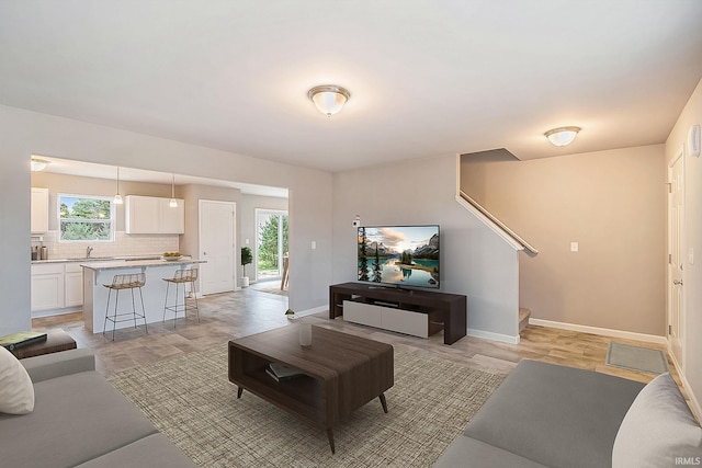 living room with sink, light hardwood / wood-style floors, and a wealth of natural light