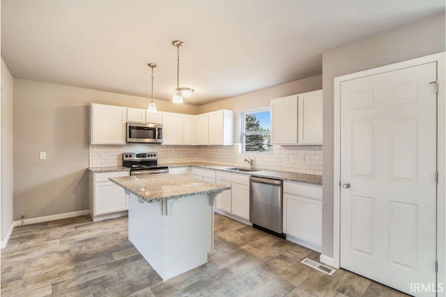 kitchen featuring a center island, appliances with stainless steel finishes, hanging light fixtures, and white cabinets