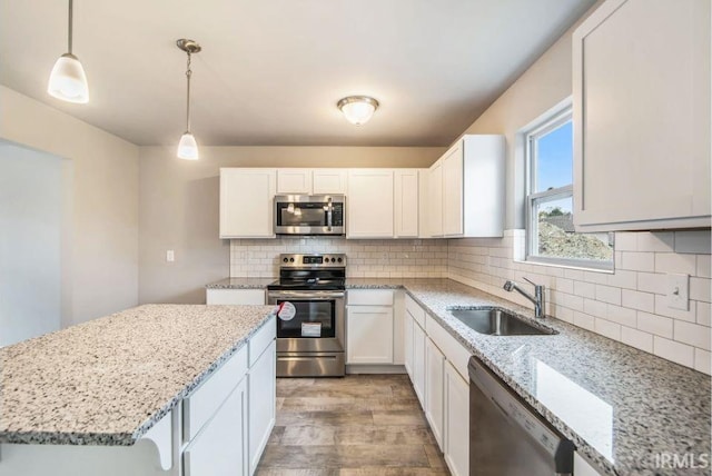 kitchen with sink, white cabinetry, decorative light fixtures, and stainless steel appliances