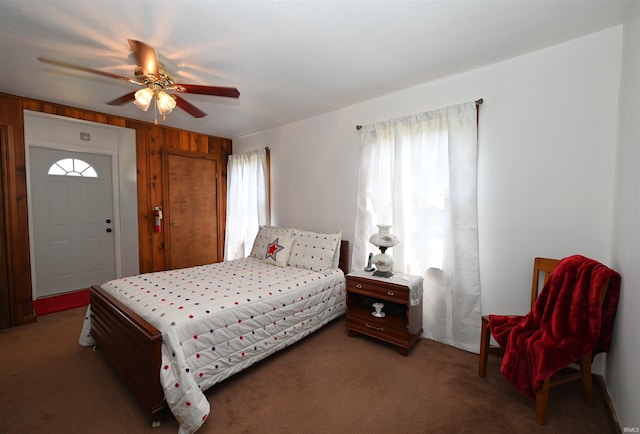 bedroom with wood walls, ceiling fan, and carpet