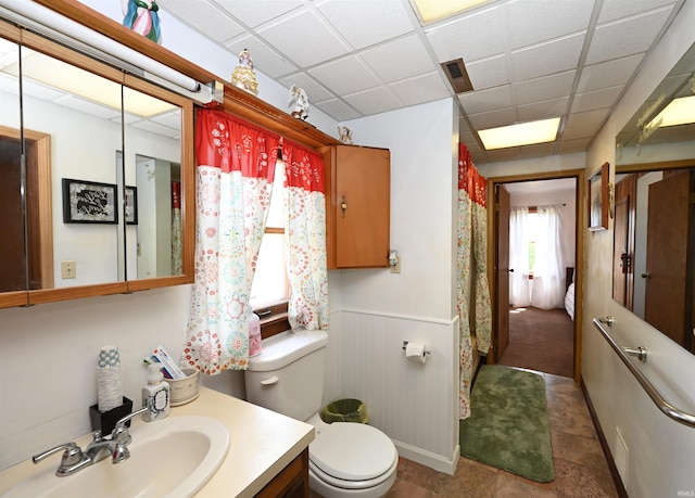 bathroom featuring a drop ceiling, tile patterned flooring, vanity, and toilet