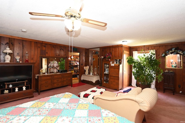 living room featuring ceiling fan, carpet, a textured ceiling, and wood walls