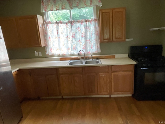 kitchen featuring sink, light wood-type flooring, refrigerator, and stove