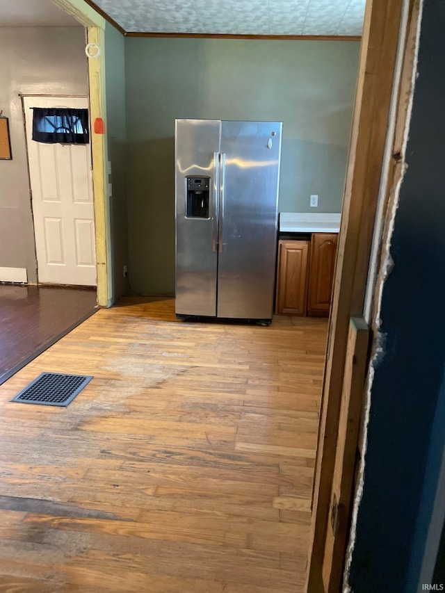 kitchen featuring stainless steel fridge with ice dispenser, light hardwood / wood-style flooring, and ornamental molding