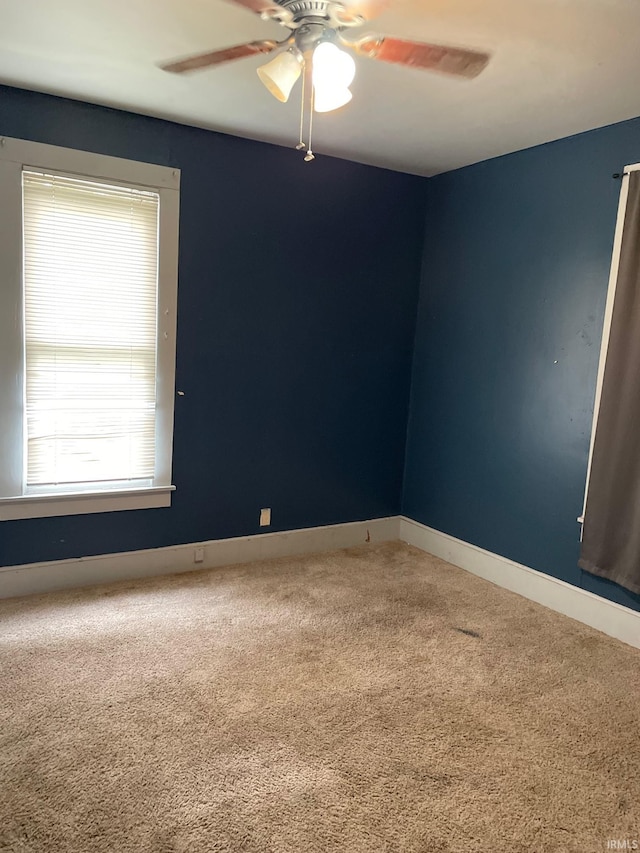 carpeted spare room featuring ceiling fan and a healthy amount of sunlight