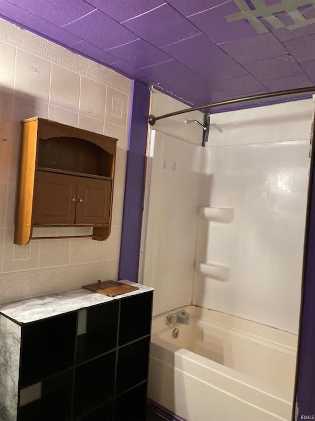 bathroom with bathing tub / shower combination, decorative backsplash, and tile walls