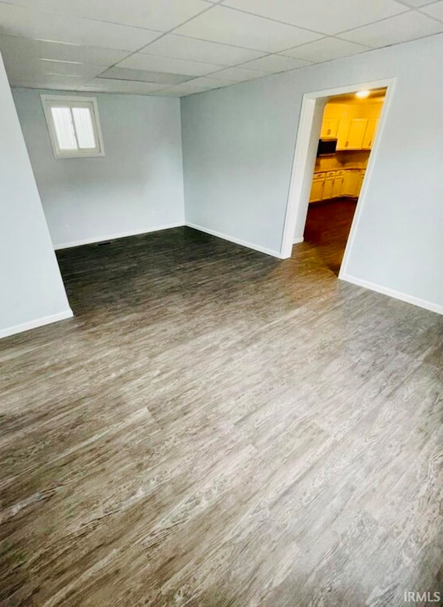 spare room with dark wood-type flooring and a paneled ceiling