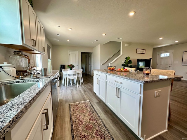 kitchen featuring a kitchen island, dark wood-type flooring, white cabinets, and stone counters