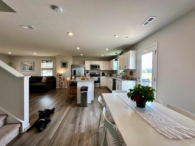 dining room featuring hardwood / wood-style floors, a wealth of natural light, sink, and a textured ceiling