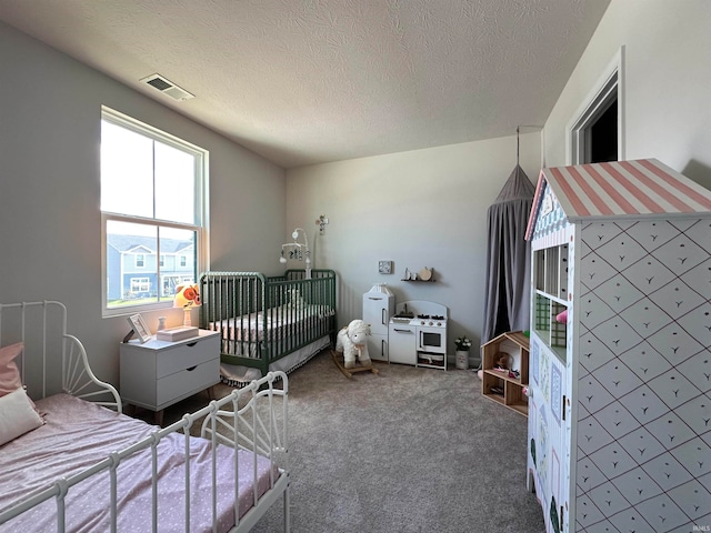 bedroom featuring carpet, a nursery area, and a textured ceiling