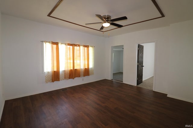 empty room with visible vents, dark wood-type flooring, and a ceiling fan