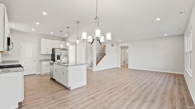 kitchen featuring light hardwood / wood-style floors, appliances with stainless steel finishes, a kitchen island with sink, and white cabinets