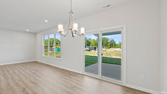 unfurnished dining area featuring light hardwood / wood-style floors and an inviting chandelier