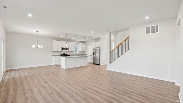 unfurnished living room featuring light wood-type flooring, sink, and an inviting chandelier