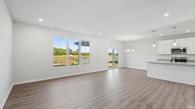 unfurnished living room with light hardwood / wood-style flooring and an inviting chandelier